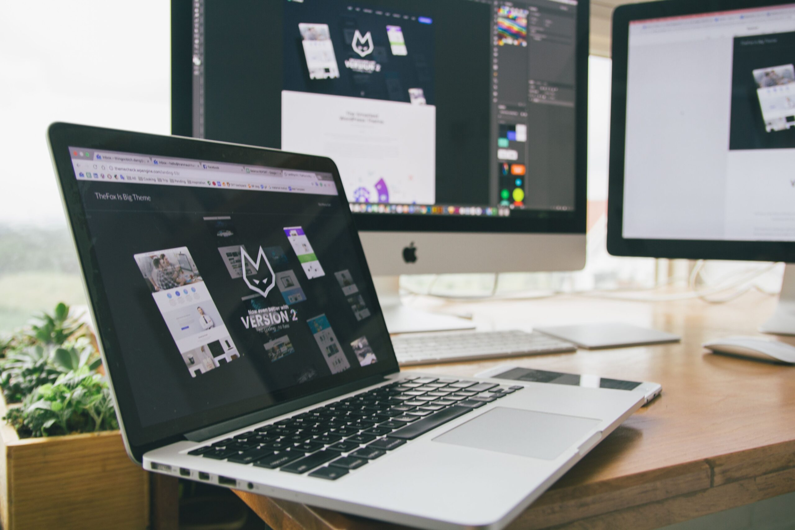 Stanowisko projektanta stron internetowych z laptopem i monitorami